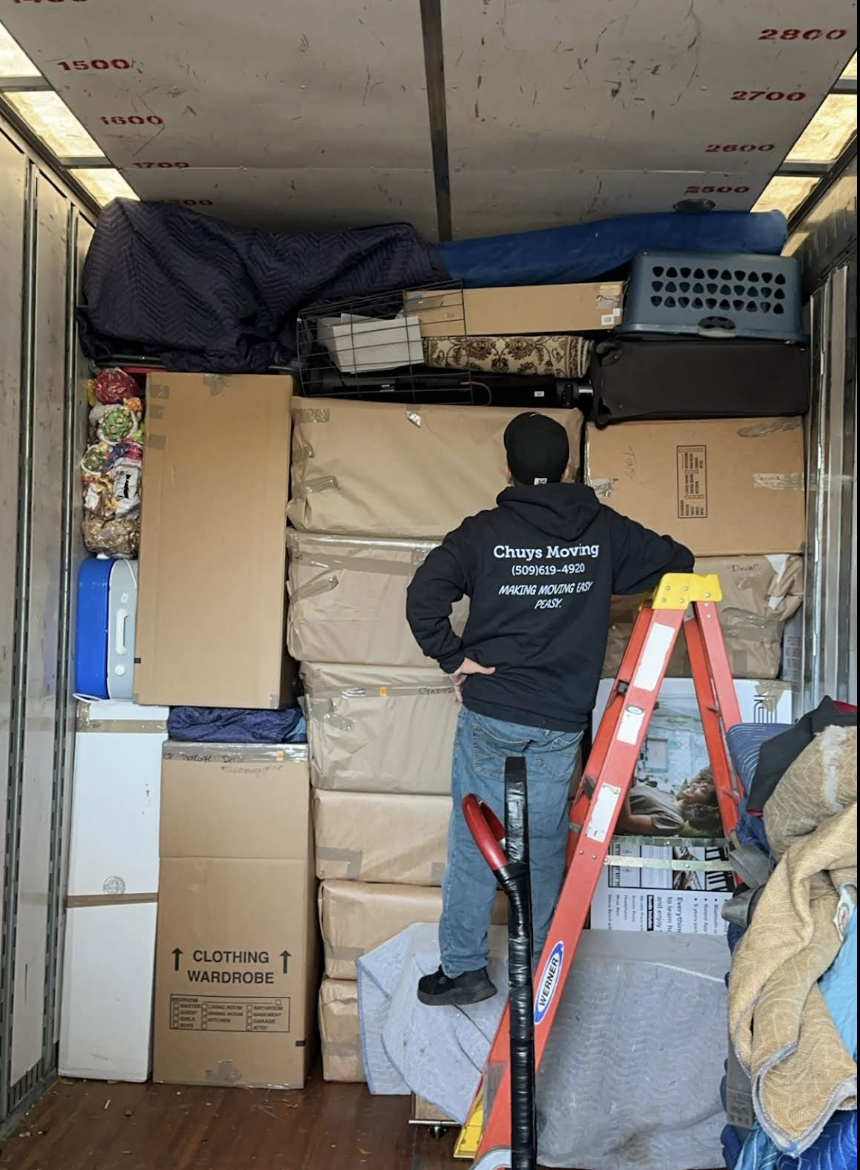 A Chuy's Moving crew member standing inside a fully packed truck showing a carefully secured load