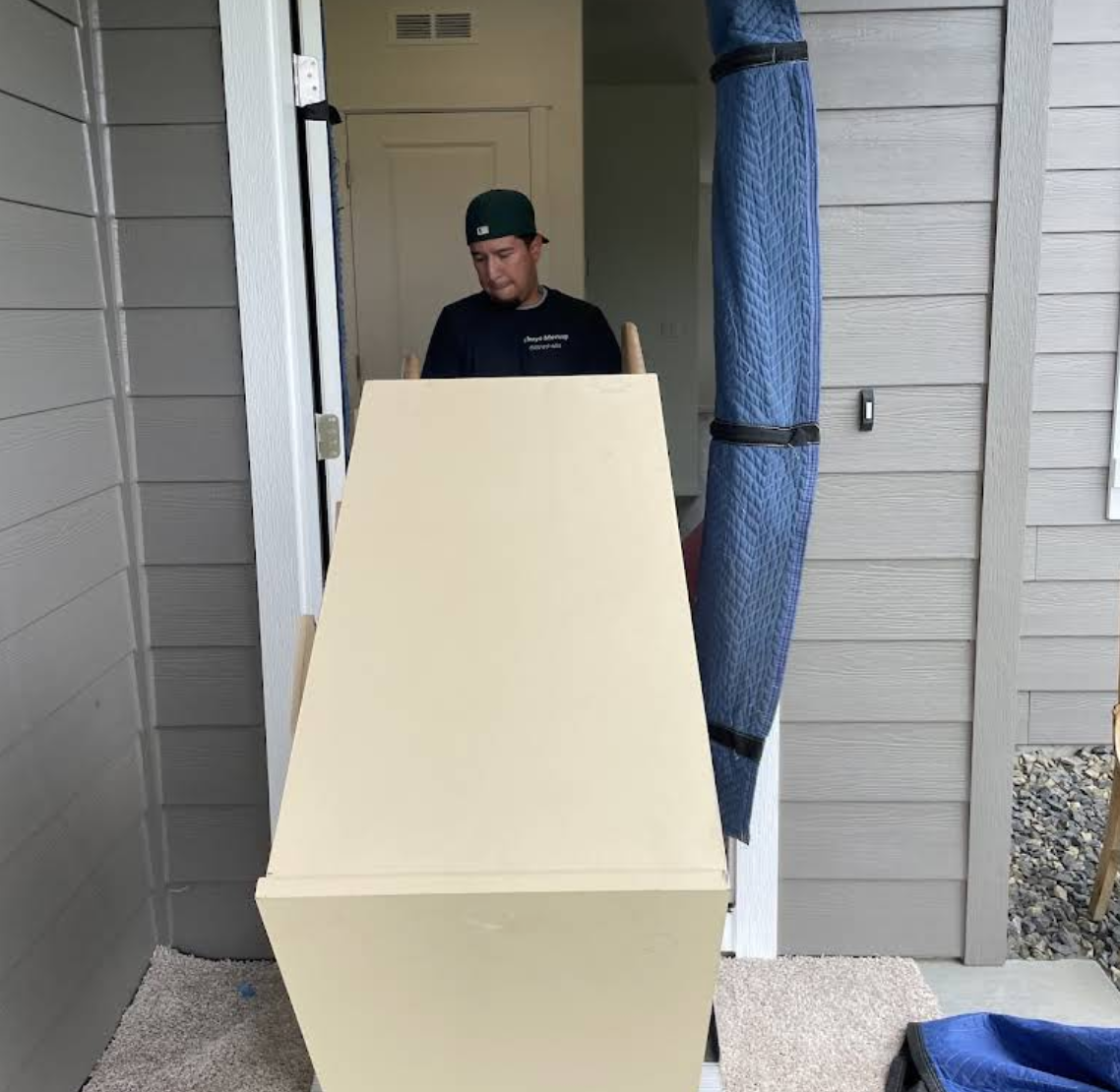 A Chuy's Moving team member carefully moving a dresser through a doorway