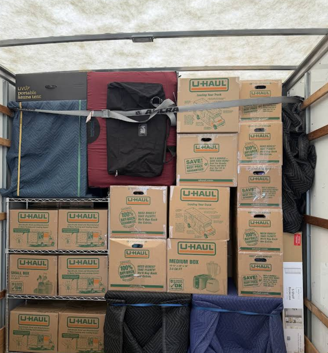 A full moving truck wall stacked with labeled boxes and padded furniture