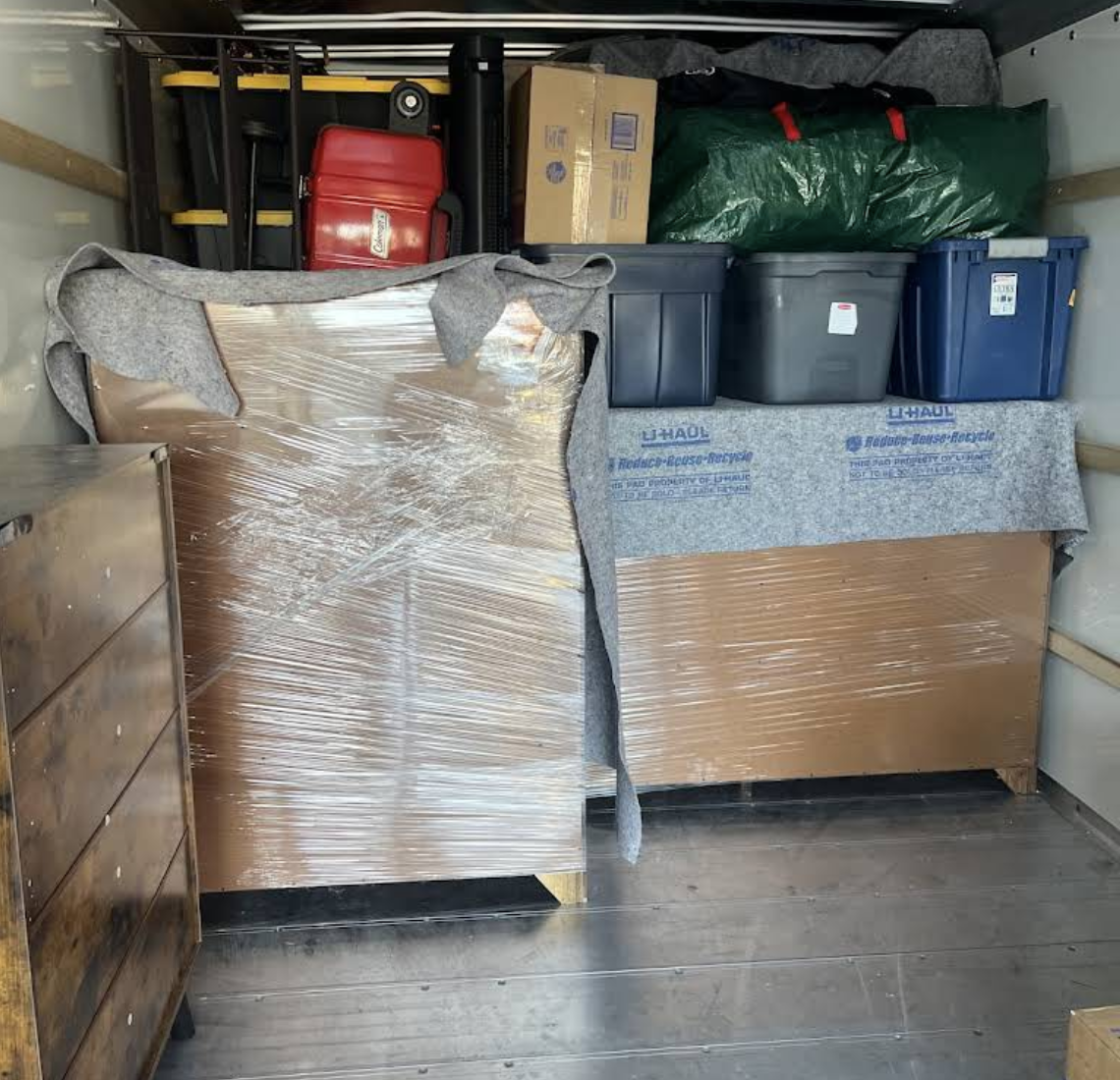 Wrapped furniture and storage bins professionally secured inside a moving truck