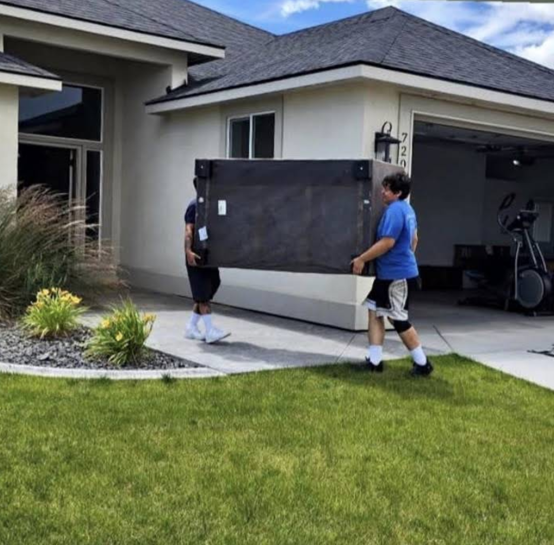 Chuy's Moving crew carrying a heavy furniture piece into a home