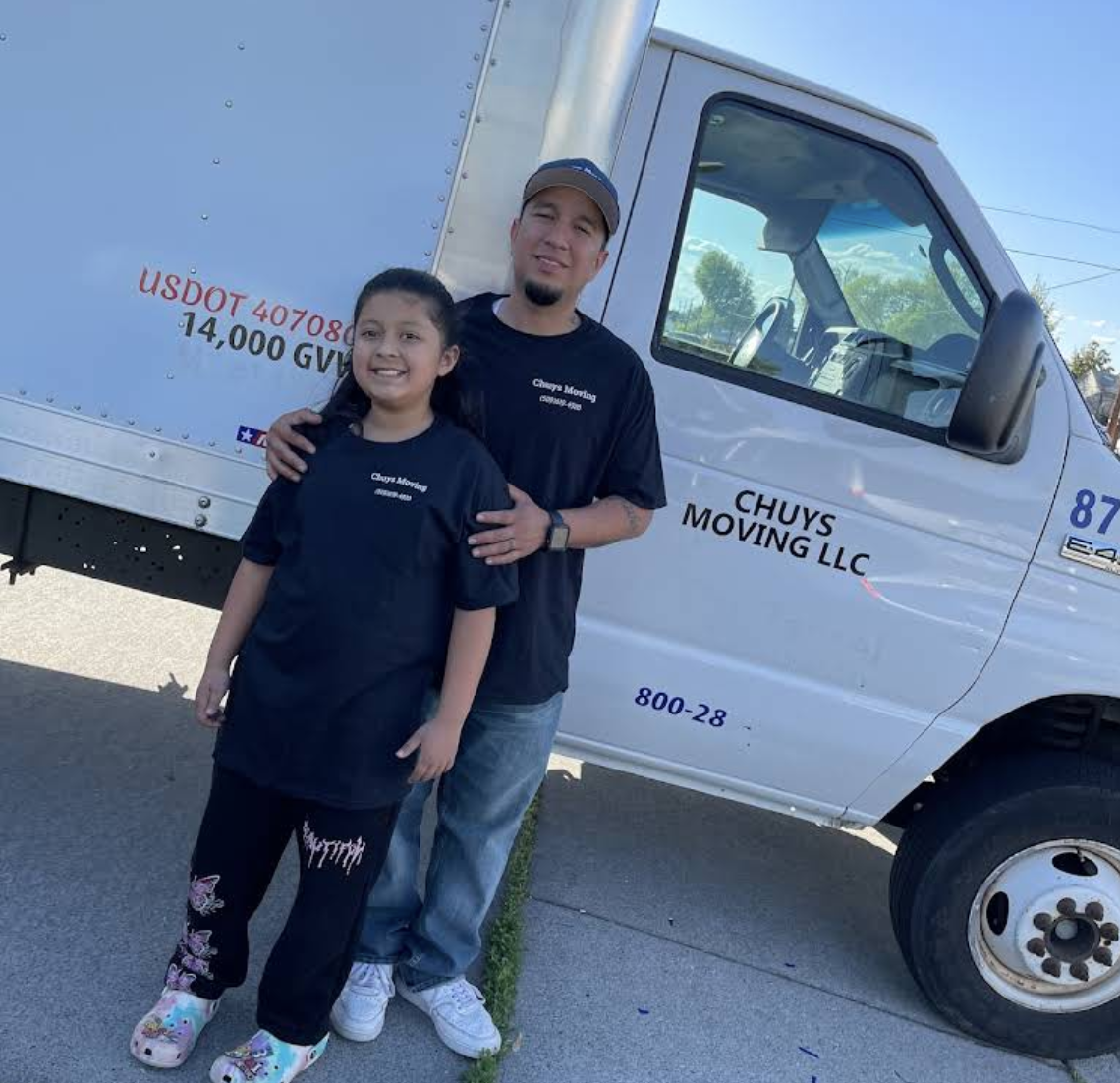 Chuy's Moving owner and child standing proudly beside the company truck